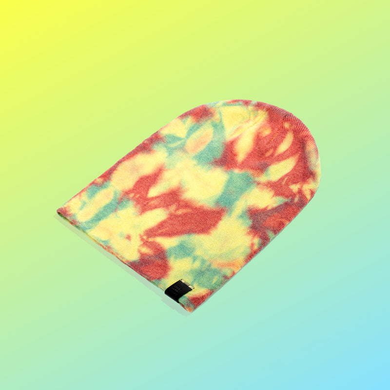 Tie-dyed beanie flattened out on a yellow and blue gradient background
