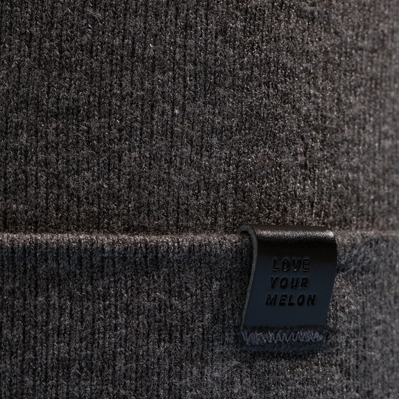 Close-up photo of dark gray beanie showing the Love Your Melon logo
