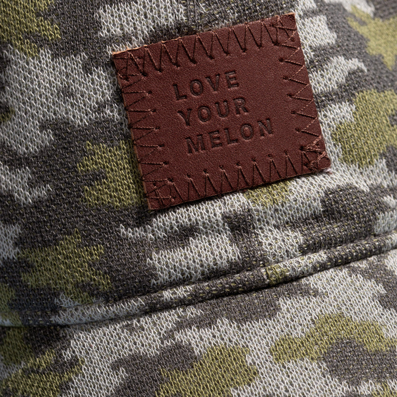 Close-up photo of a camo-patterned cap to show the logo